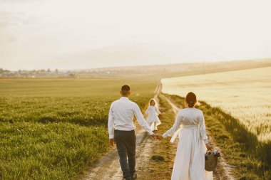 Küçük kızı olan bir aile güneşli bir arazide birlikte vakit geçiriyor.