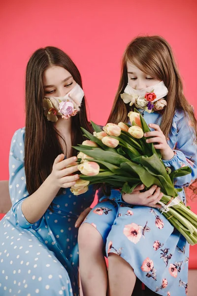Kırmızı arka planda çiçekli maskeli kızlar