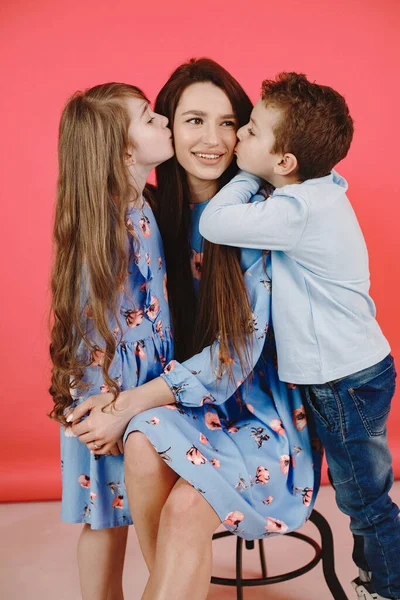 Kırmızı arka planda kızı ve oğlu olan bir anne.