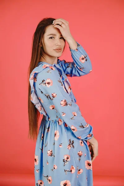 Chica en un vestido azul sobre un fondo rojo — Foto de Stock