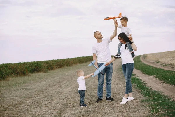 Family walks in a field and playing with toy plane