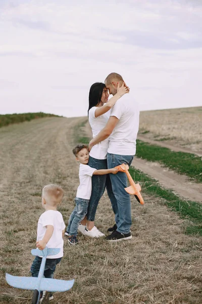 La famille marche dans un champ et joue avec un avion jouet — Photo