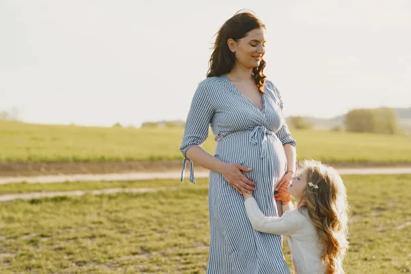 Zwangere moeder met haar dochter in een veld — Stockfoto