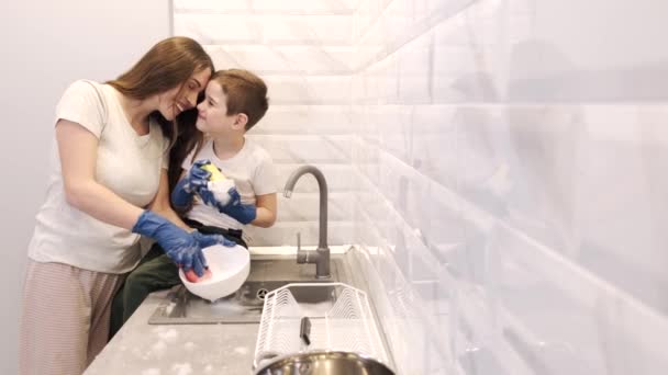 Mother and little son washing the dishes together in gloves — Stock Video