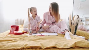 Güzel anne yatakta kızıyla sayfaları topluyor.