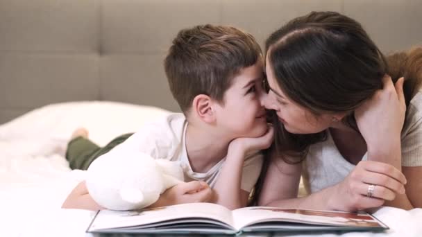 Glückliche Mutter und Sohn lesen gemeinsam Buch im Bett — Stockvideo