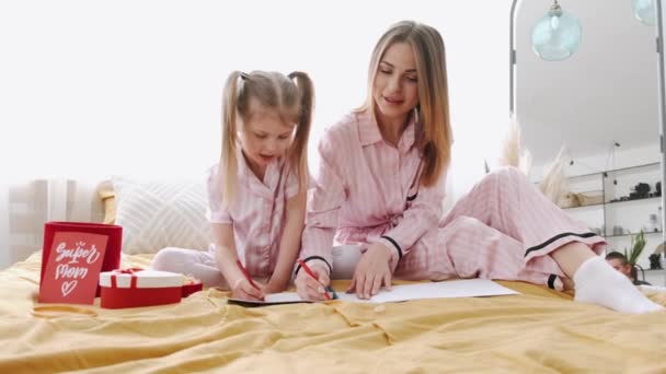 Όμορφη μητέρα χρωματίζοντας σελίδες με την κόρη στο κρεβάτι — Αρχείο Βίντεο