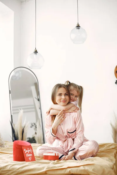 귀여운 딸을 침대에 안고 있는 어린 어머니 — 스톡 사진
