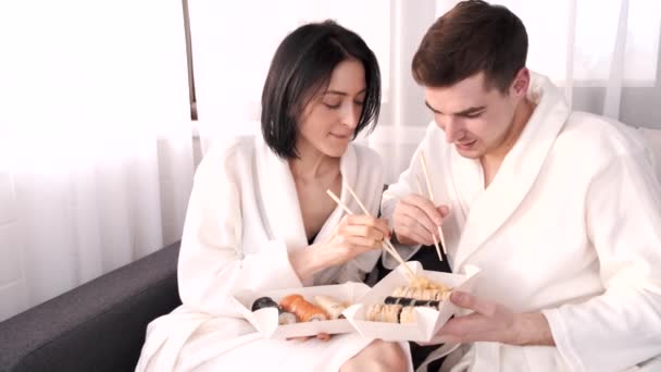 Two young people eat sushi rolls at home — Stock Video