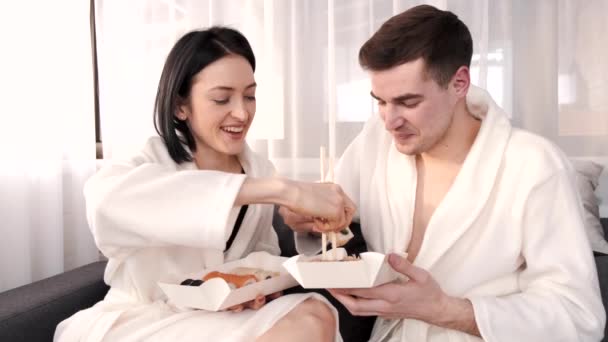 Двое молодых людей едят суши-роллы дома — стоковое видео