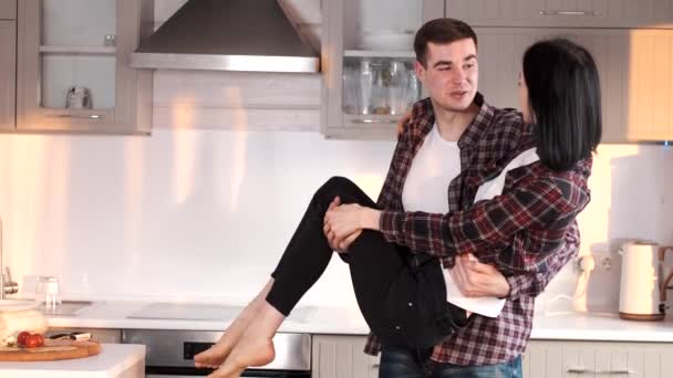 Чоловік, що носить свою дівчину, перебуваючи на кухні — стокове відео