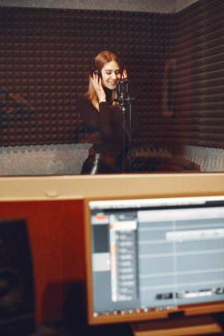 Bir stüdyoda mikrofonla şarkı söylemek ve çalışmak.