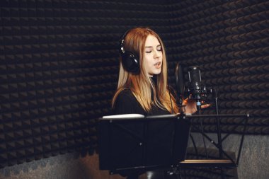 Bir stüdyoda mikrofonla şarkı söylemek ve çalışmak.