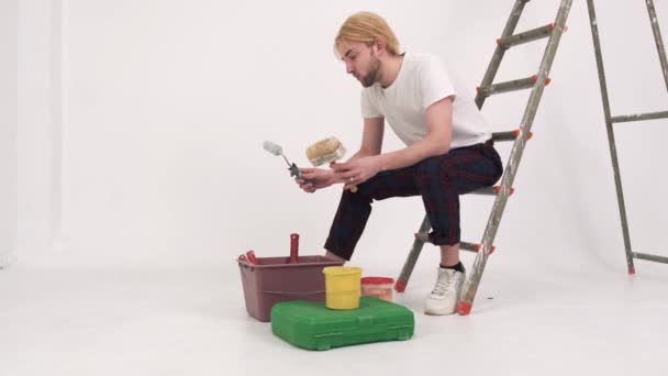 Mladý muž sedí na žebříku a kontroluje nástroje — Stock video