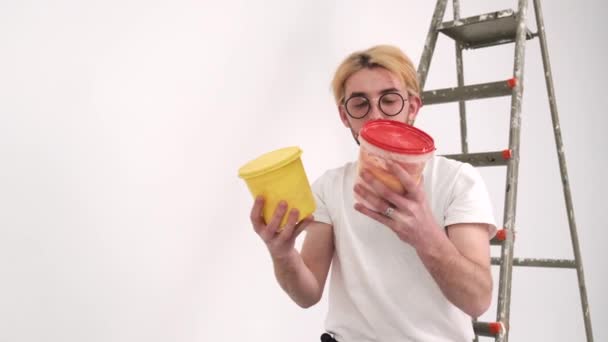 Человек в очках держит два ведра для украшения стен — стоковое видео