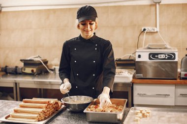 Üniformalı kadın aşçı ticari mutfakta yemek pişiriyor.