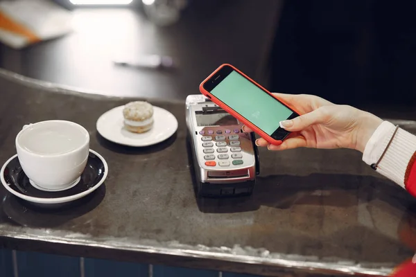 Girl paying for her latte with a smartphone by contactless PAY PASS technology
