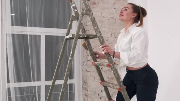 Pareja joven pintando paredes juntas en un nuevo hogar — Vídeo de stock