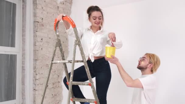 Pareja joven pintando paredes juntas en un nuevo hogar — Vídeo de stock