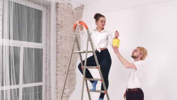 Jong stel schilderen muren samen in nieuw huis — Stockvideo