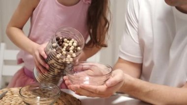 Önemseyen baba ve küçük kız mısır gevreğine süt ekliyor.