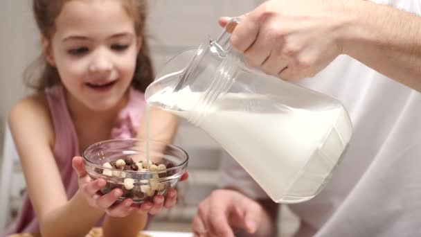 Gondoskodó apa és kislánya tejet adnak a kukoricapelyhekhez. — Stock videók