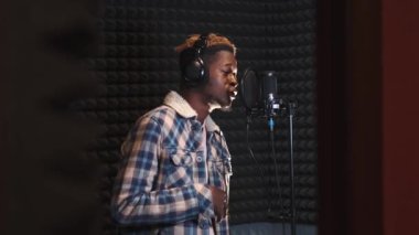 Kayıt stüdyosunda şarkı söyleyen genç adam.