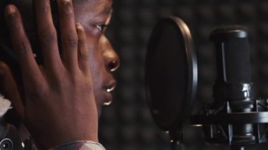 Kayıt stüdyosunda şarkı söyleyen genç adam.