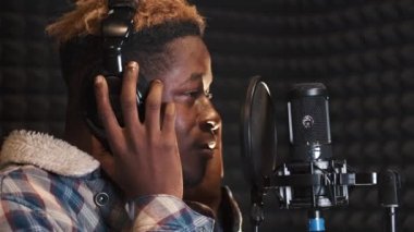 Kayıt stüdyosunda şarkı söyleyen genç adam.