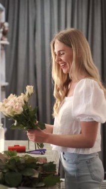 Güzel bayan çiçekçi bir dükkanda buket düzenliyor.