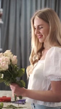 Güzel bayan çiçekçi bir dükkanda buket düzenliyor.