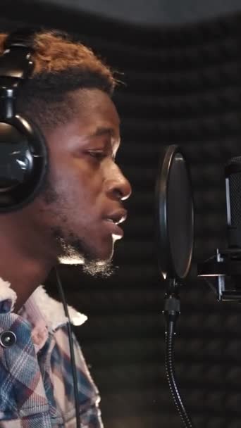 Молодой парень поет в студии звукозаписи — стоковое видео