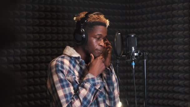 Молодой парень поет в студии звукозаписи — стоковое видео