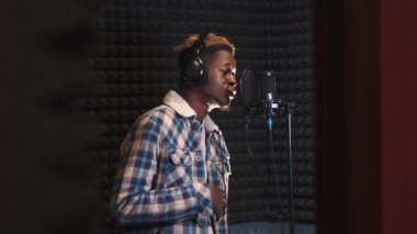 Kayıt stüdyosunda şarkı söyleyen genç adam.