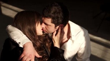 Tutkulu bir çift stüdyoda gün ışığında öpüşüyor.