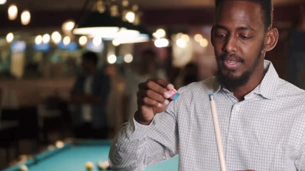 African American guy rubbing chalk on a cue — Video