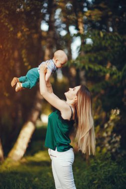 Anne ve küçük oğlu yaz parkında oynuyorlar.