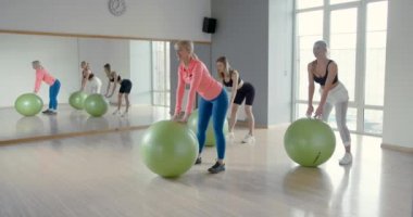 Beden eğitimi sınıfında toplarla antrenman yapan bir grup kadın.