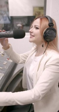 Mutlu genç bayan radyo sunucusu stüdyoda yayın yapıyor.