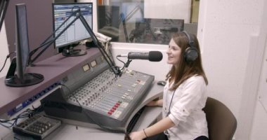 Mutlu genç bayan radyo sunucusu stüdyoda yayın yapıyor.