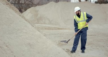 İnşaat alanında kürekle kum kazan el işçisi.