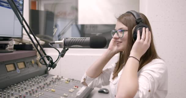 Χαμογελαστή νεαρή γυναίκα παρουσιάστρια ραδιοφωνικών εκπομπών στο στούντιο — Αρχείο Βίντεο