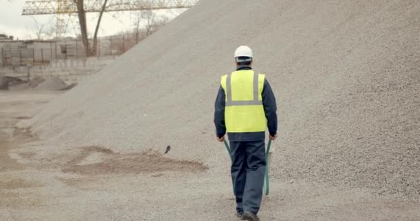 Pracownik fizyczny kopiący piasek łopatą na placu budowy — Wideo stockowe