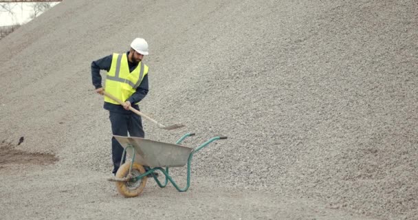Trabajador manual excavando arena con pala en obra — Vídeo de stock