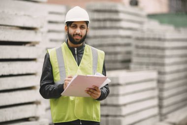 İnşaat mühendisi dışarıda kaskla çalışıyor.