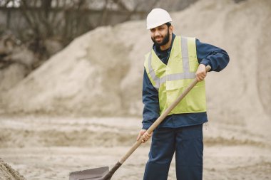İnşaat mühendisi dışarıda kaskla çalışıyor.