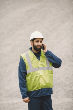 İnşaat mühendisi dışarıda kaskla çalışıyor.