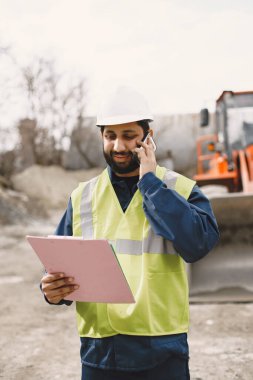 İnşaat mühendisi dışarıda kaskla çalışıyor.