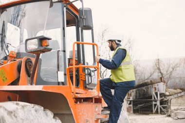 İnşaat mühendisi dışarıda kaskla çalışıyor.