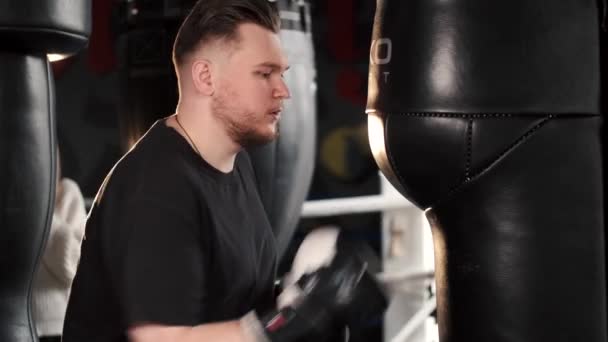 Joven boxeo y saco de boxeo en gimnasio — Vídeo de stock